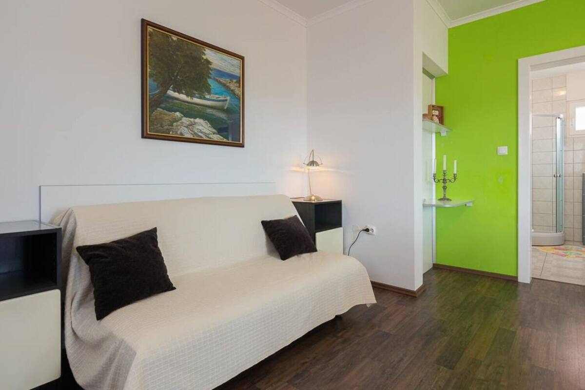 Ein Zimmer mit einem Bett, einem Nachttisch, einer Lampe und einem Bild an der Wand.