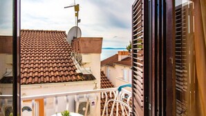 Ein Balkon mit Ziegeldach, einer Satellitenschüssel und einem kleinen Tisch mit Blumentöpfen.