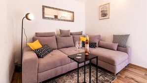 Ein modernes Wohnzimmer mit einer Sofagarnitur, einem kleinen Couchtisch, einer Stehlampe und einem gerahmten Bild an der Wand.