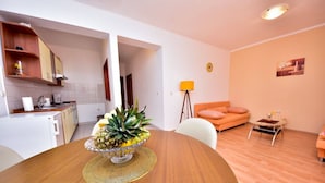 A modern kitchen with white cabinets and a dining area with a wooden table and chairs. - Apartment Roko (Obrovac)