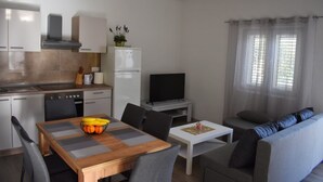 Ett kompakt bostadsutrymme med kök, matplats och sittgrupp.