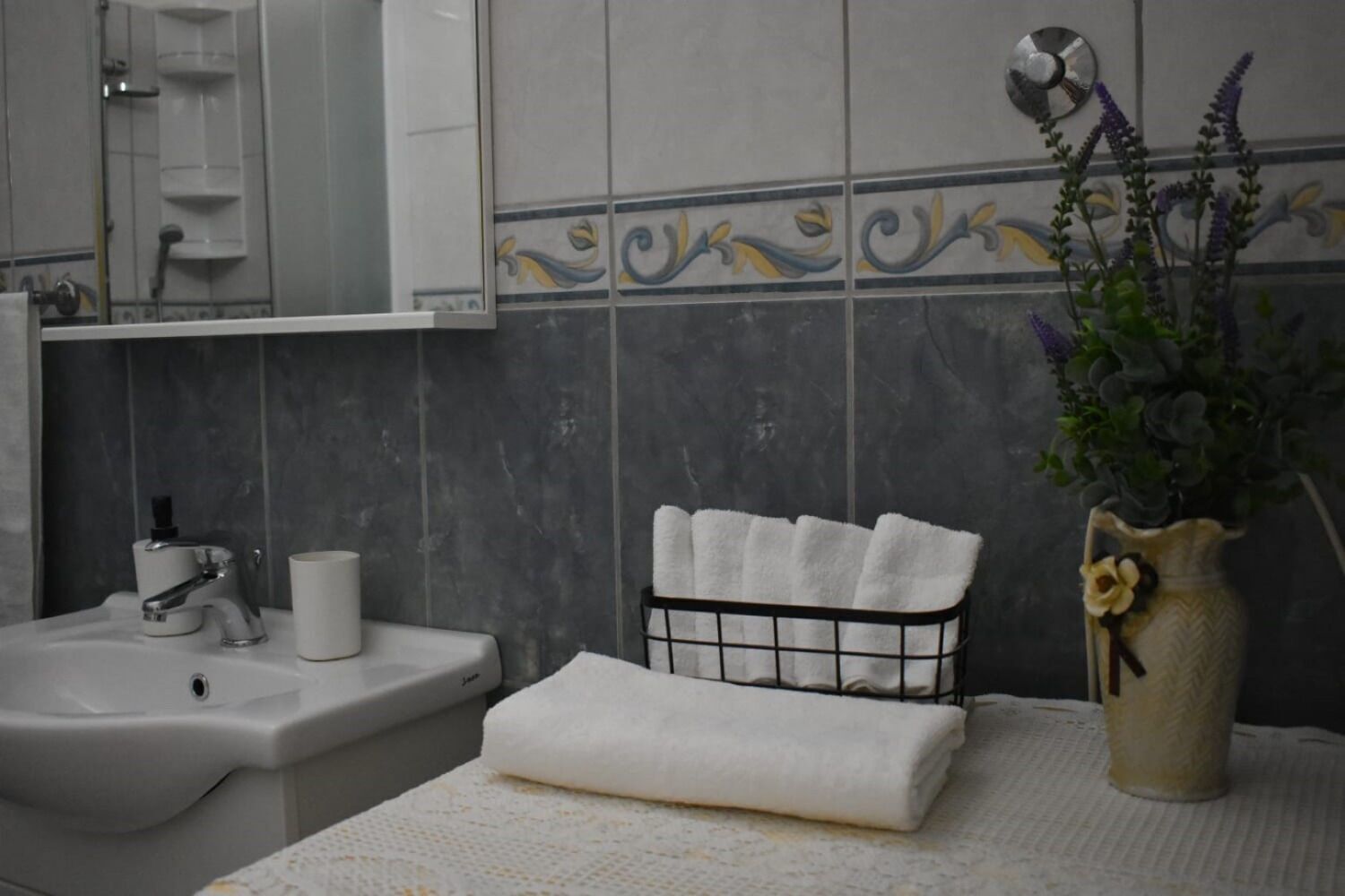 Un bagno con lavandino, specchio e porta asciugamani con asciugamani piegati.