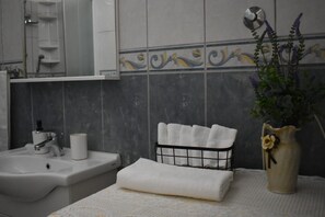 A bathroom with a sink, mirror, and a towel rack with folded towels.