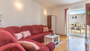 A modern living room with a red sofa, a white coffee table, and a large mirror. - Apartments and Rooms Happiness (Tucepi)