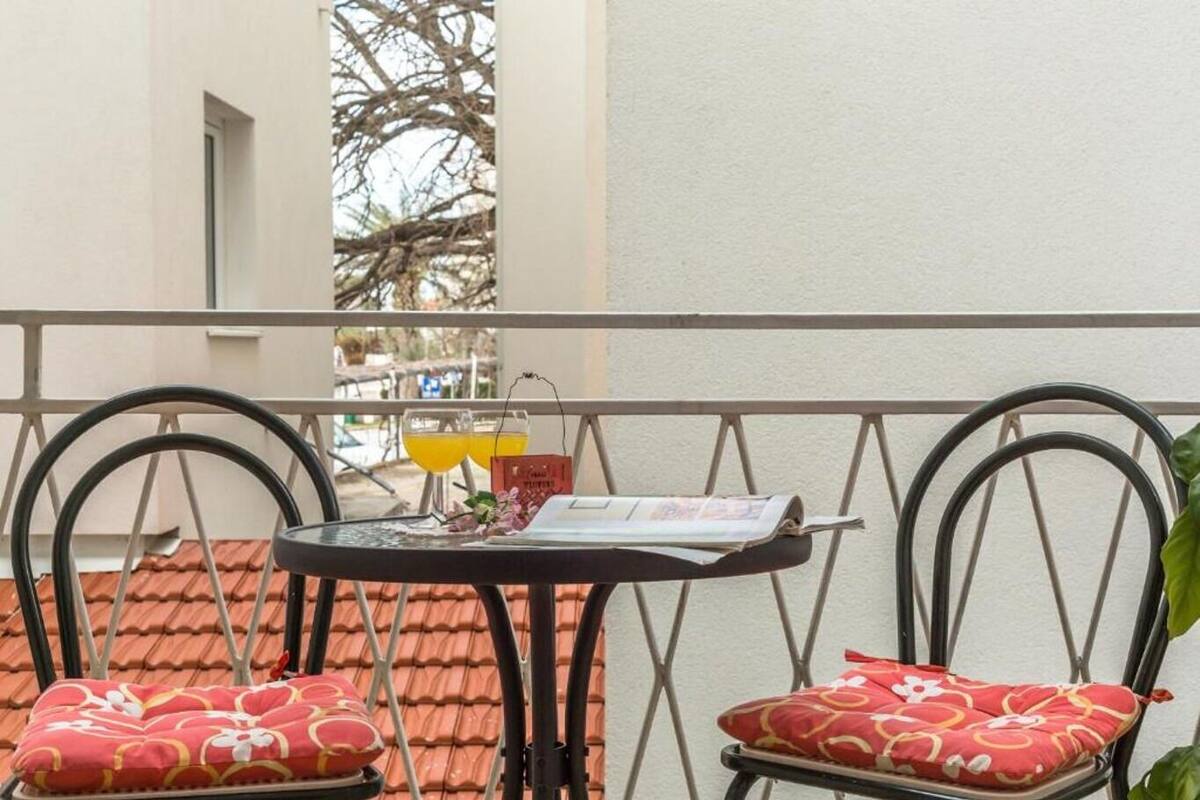 A balcony with two chairs, a small table, and a newspaper.