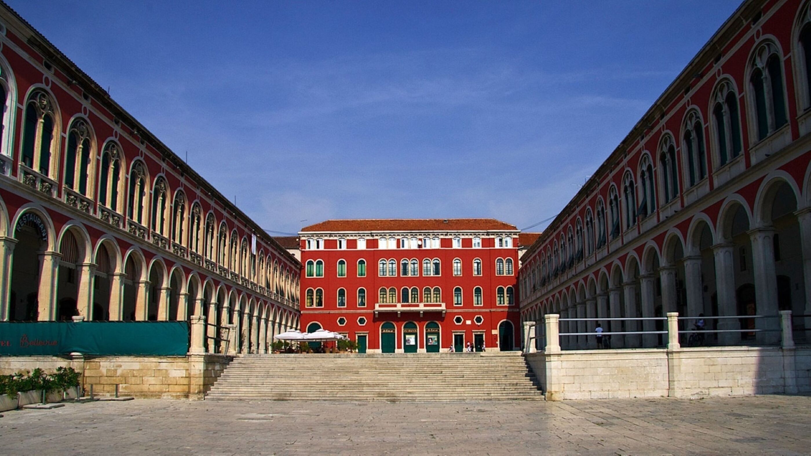 A large red building with multiple arched windows and a central entrance.