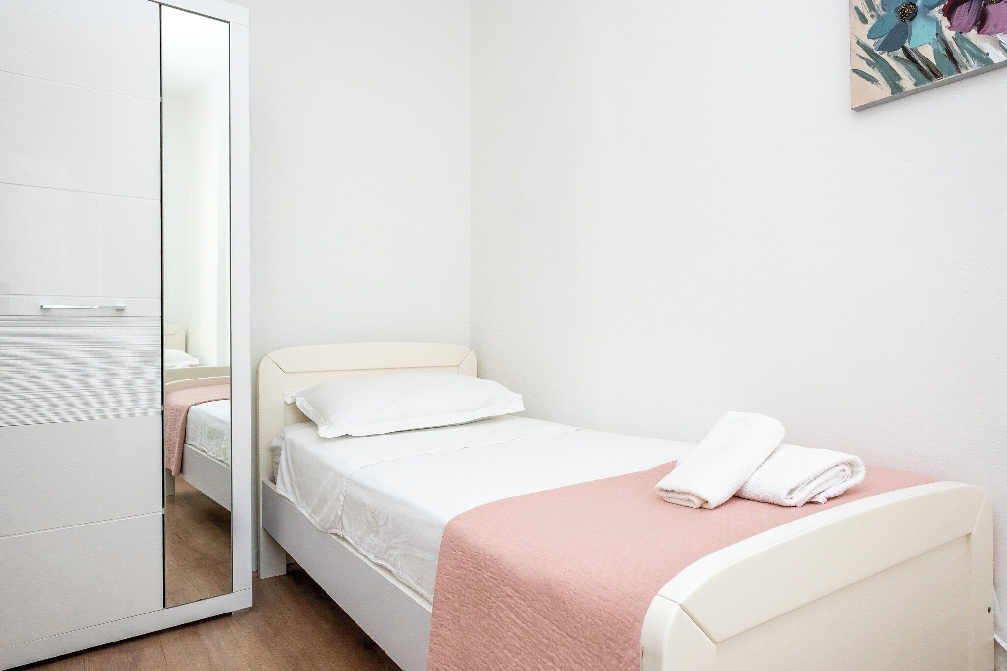A bedroom with a bed, a wardrobe, and a mirror.