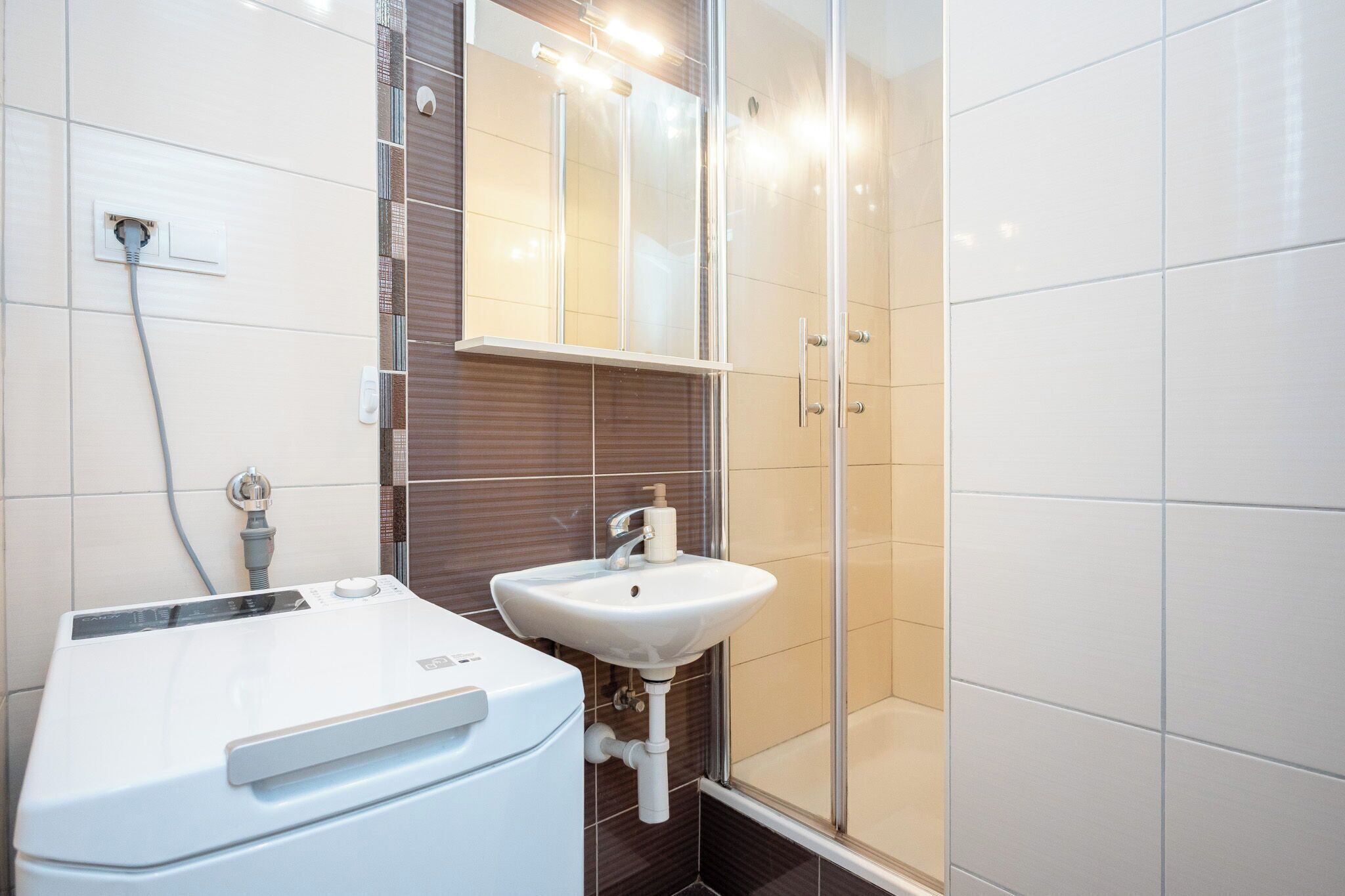 A modern bathroom with a white sink, a glass shower enclosure, and a built-in toilet.
