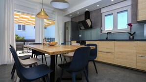 A modern kitchen with a wooden dining table, blue chairs, and pendant lights. - House Kreso (Sibenik)