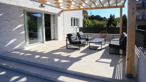 An outdoor patio area with a pergola, a sofa, a chair, and a small table. - House Kreso (Sibenik)