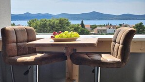 Un balcón con dos sillones acolchados y una mesa con un frutero.