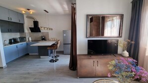 Una cocina moderna con una isla central, taburetes de bar, un televisor de pantalla plana y un jarrón decorativo con flores.