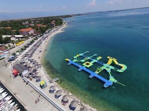 Vista aérea de una zona costera con playa, puerto deportivo y estructura flotante con rampas.