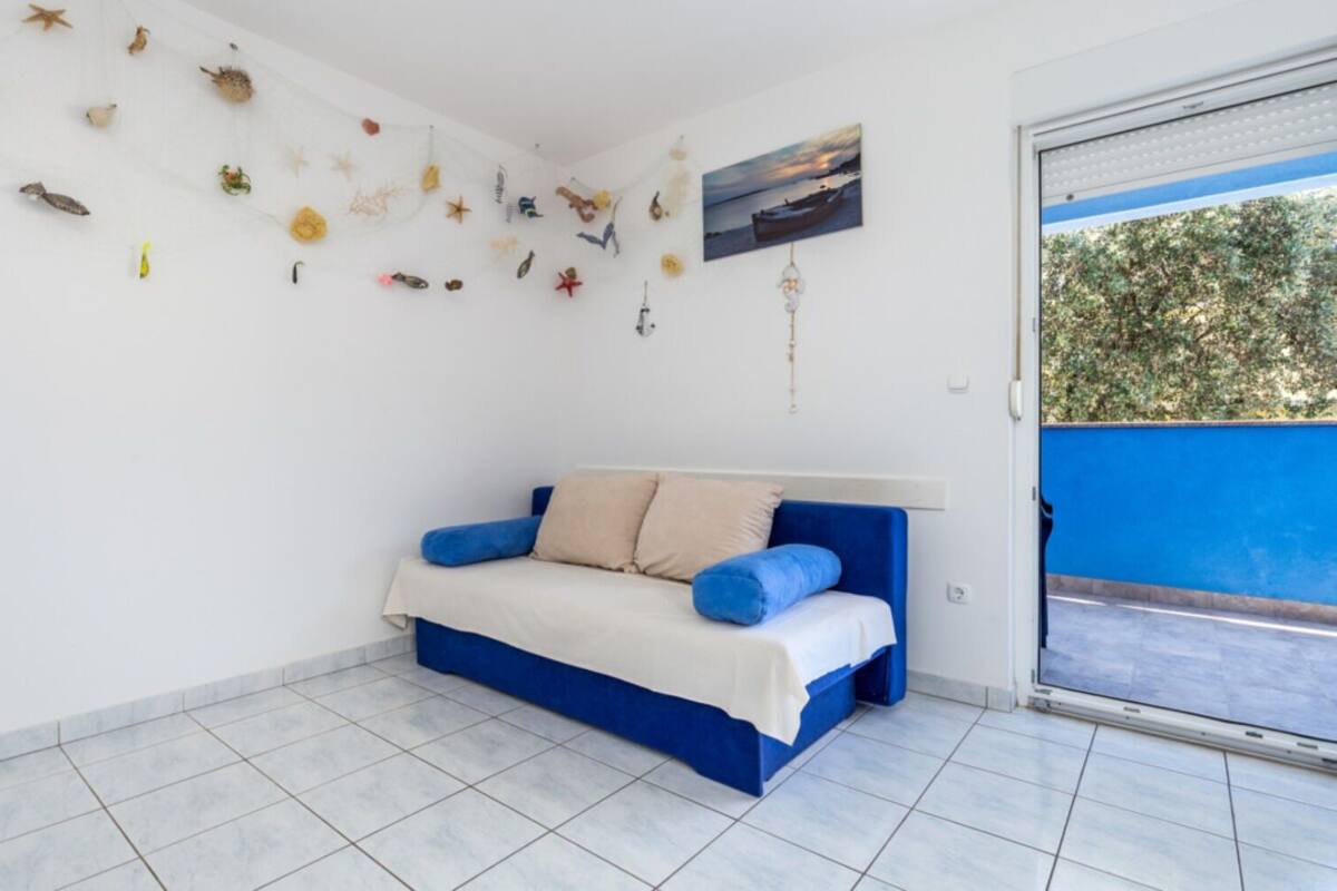 Une chambre à coucher avec un lit bleu et blanc, une petite fenêtre et un mur décoré de divers objets.