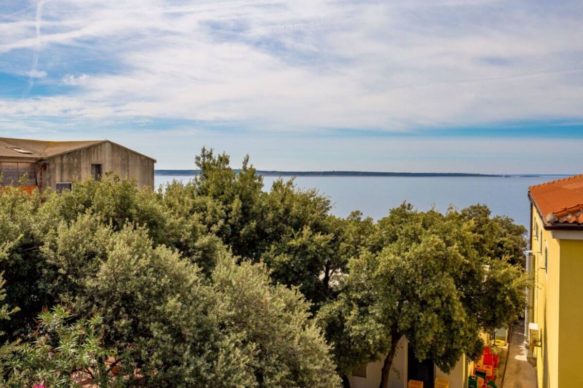 Une vue côtière avec un bâtiment au premier plan et une étendue d’eau en arrière-plan.