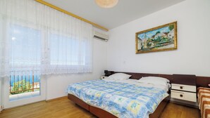 Une chambre à coucher avec un lit, une table de chevet, une commode, une fenêtre donnant sur un beau paysage et un tableau accroché au mur.