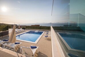 Un espace piscine sur le toit, comprenant plusieurs piscines, des chaises longues et des parasols.