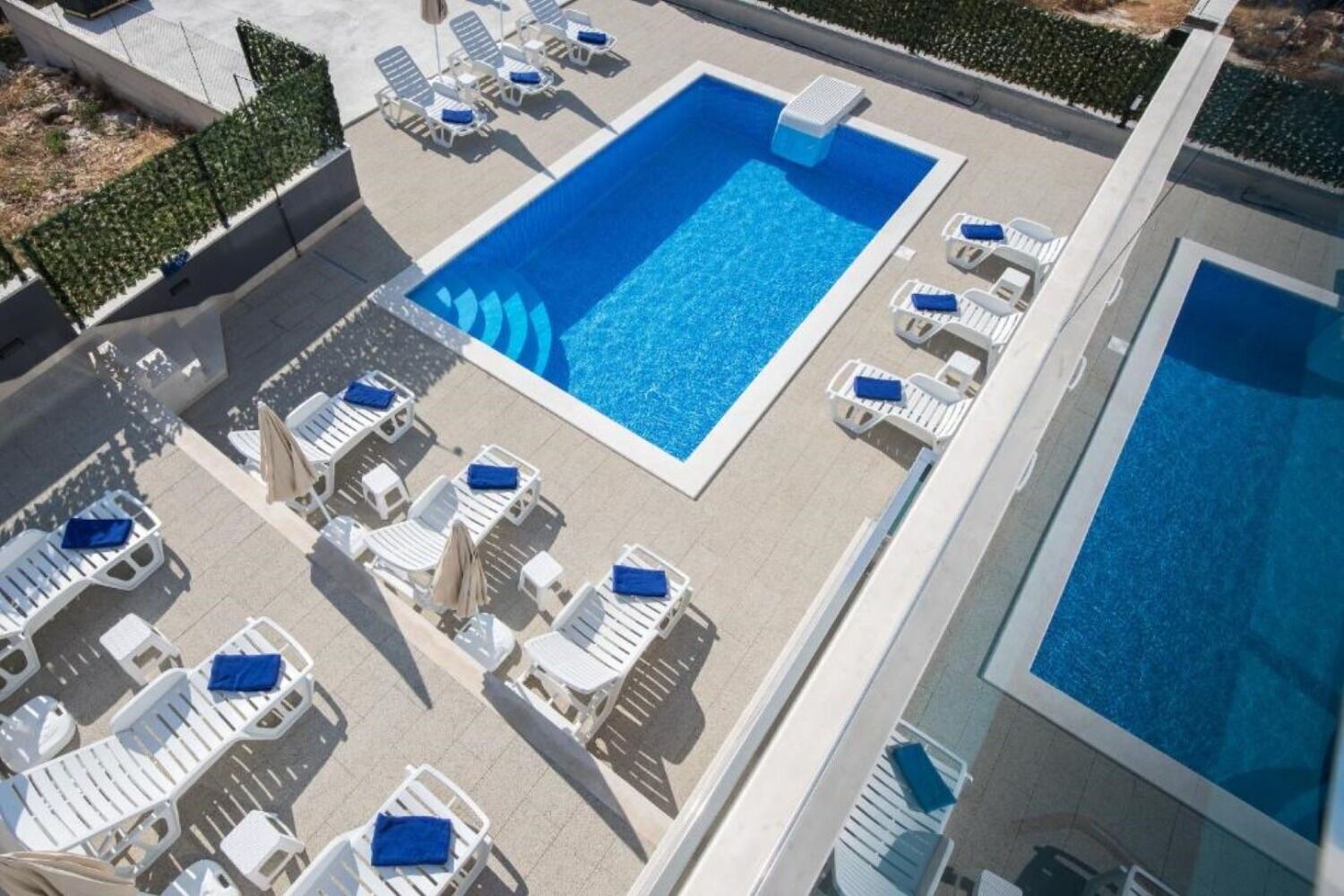 A rooftop pool area with multiple lounge chairs and a large swimming pool.