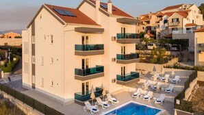 Un hôtel moderne à plusieurs étages, doté d’une piscine sur le toit, de balcons et d’un jardin aménagé.