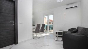 Un salon moderne avec un canapé foncé, une petite table ronde et deux chaises.