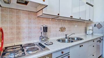 A modern kitchen with a gas stove, stainless steel sink, and white cabinets.
