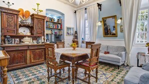 Une pièce à l’ancienne, comprenant une table à manger, des chaises, un canapé, une bibliothèque et un téléviseur.