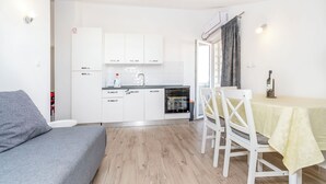Ett kompakt bostadsutrymme med ett litet kök, en matplats med bord och stolar samt en soffa.
