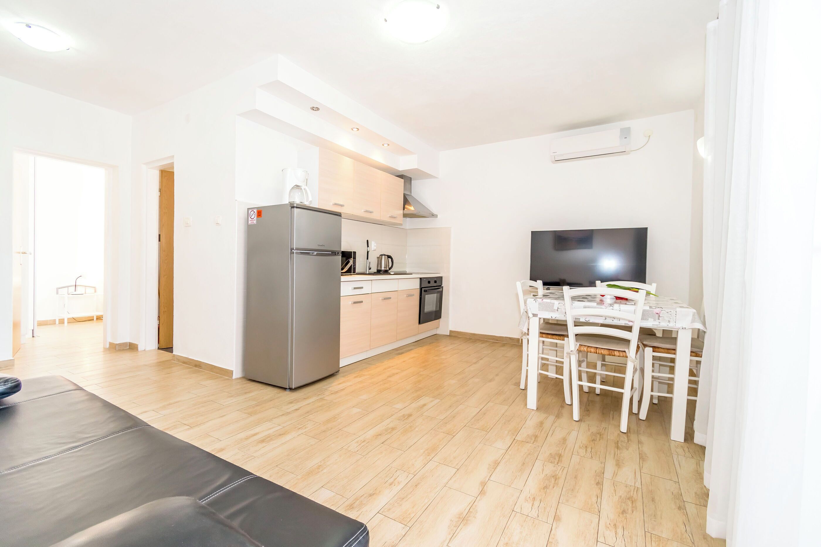 A modern kitchen with a refrigerator, stove, and dining table with chairs.