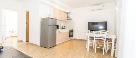 A modern kitchen with a refrigerator, stove, and dining table with chairs.