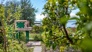 Un sentier de jardin avec un banc en pierre et un panneau indicateur vert.