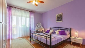 Une chambre à coucher comprenant un lit, une table de chevet, une commode et un ventilateur de plafond.