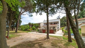 A two-story building with a driveway leading to a gated entrance. - Apartments Niki (Rab)
