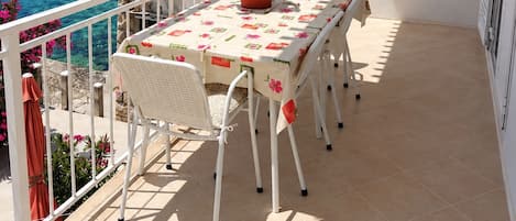 A balcony with a table, chairs, and a potted plant.