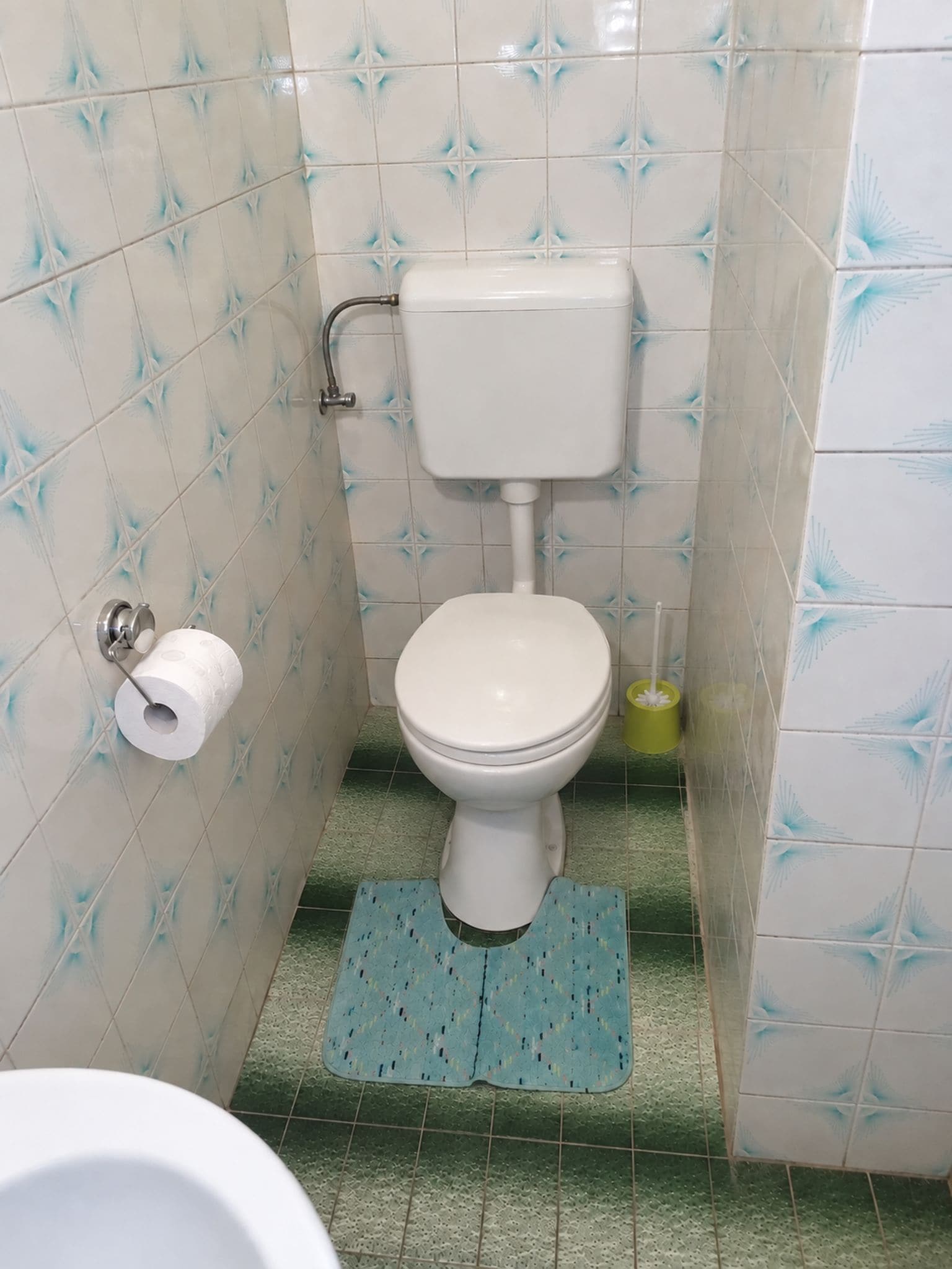A bathroom with a toilet, a toilet paper holder, and a bidet.