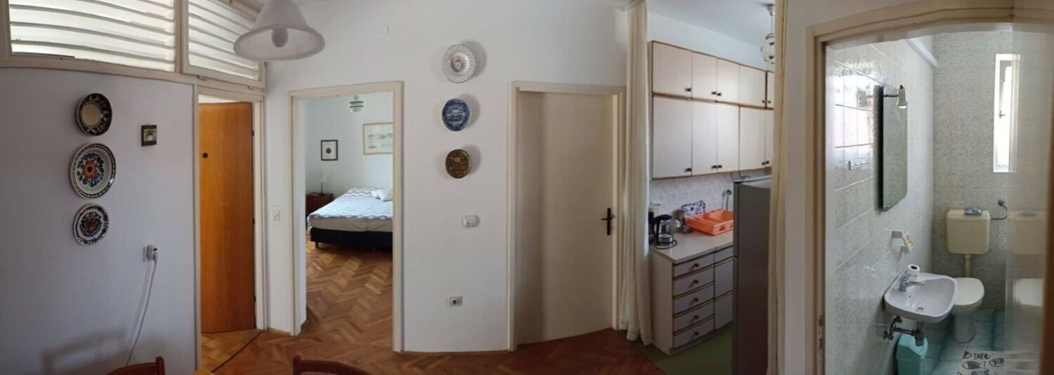 A room with a bed, a kitchenette, and a bathroom.