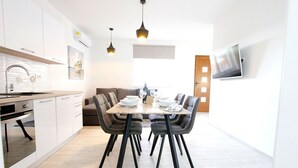 Una cocina moderna con armarios blancos, una mesa de comedor con sillas negras y luces colgantes.