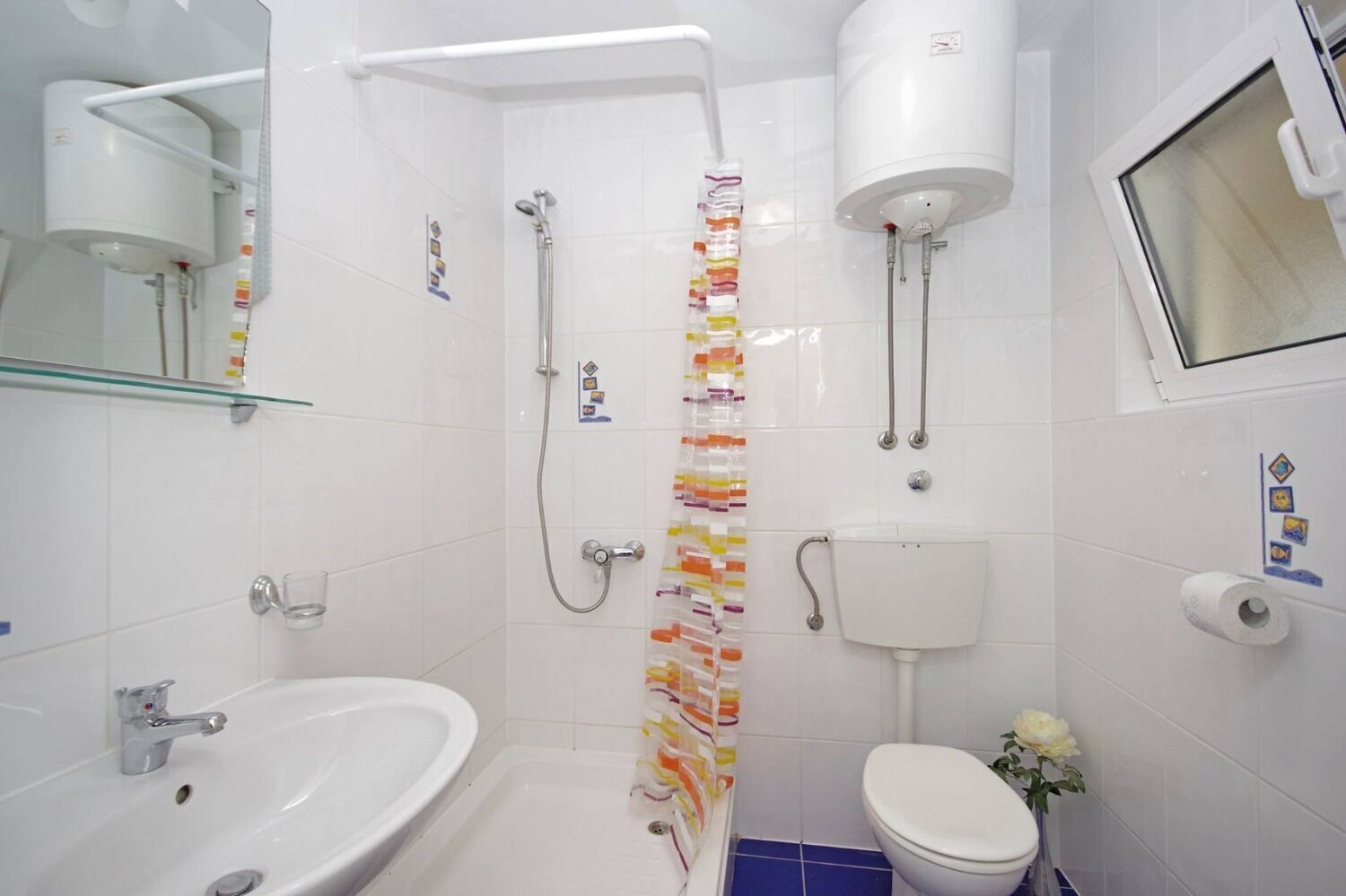 A bathroom with a shower, toilet, sink, and a glass shelf.