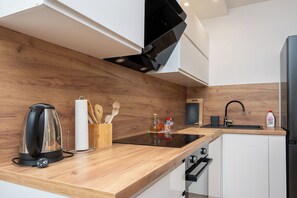 A modern kitchen with wooden countertops, a black kettle, a sink, and a stainless steel refrigerator. - Apartment Sani (Supetar)