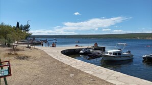 A lakeside dock with boats, a stone pathway, and a clear sky. - Apartments Sandra (Obrovac)