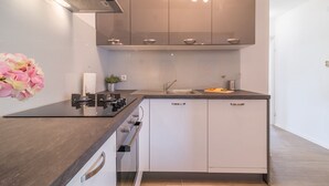 A modern kitchen with a black countertop, stainless steel appliances, and white cabinetry. - Apartments Sandra (Obrovac)