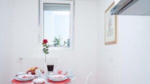 A dining area with a table set for four, a radiator, a window with a view, and a framed picture on the wall. - Apartment Asja (Zagreb)
