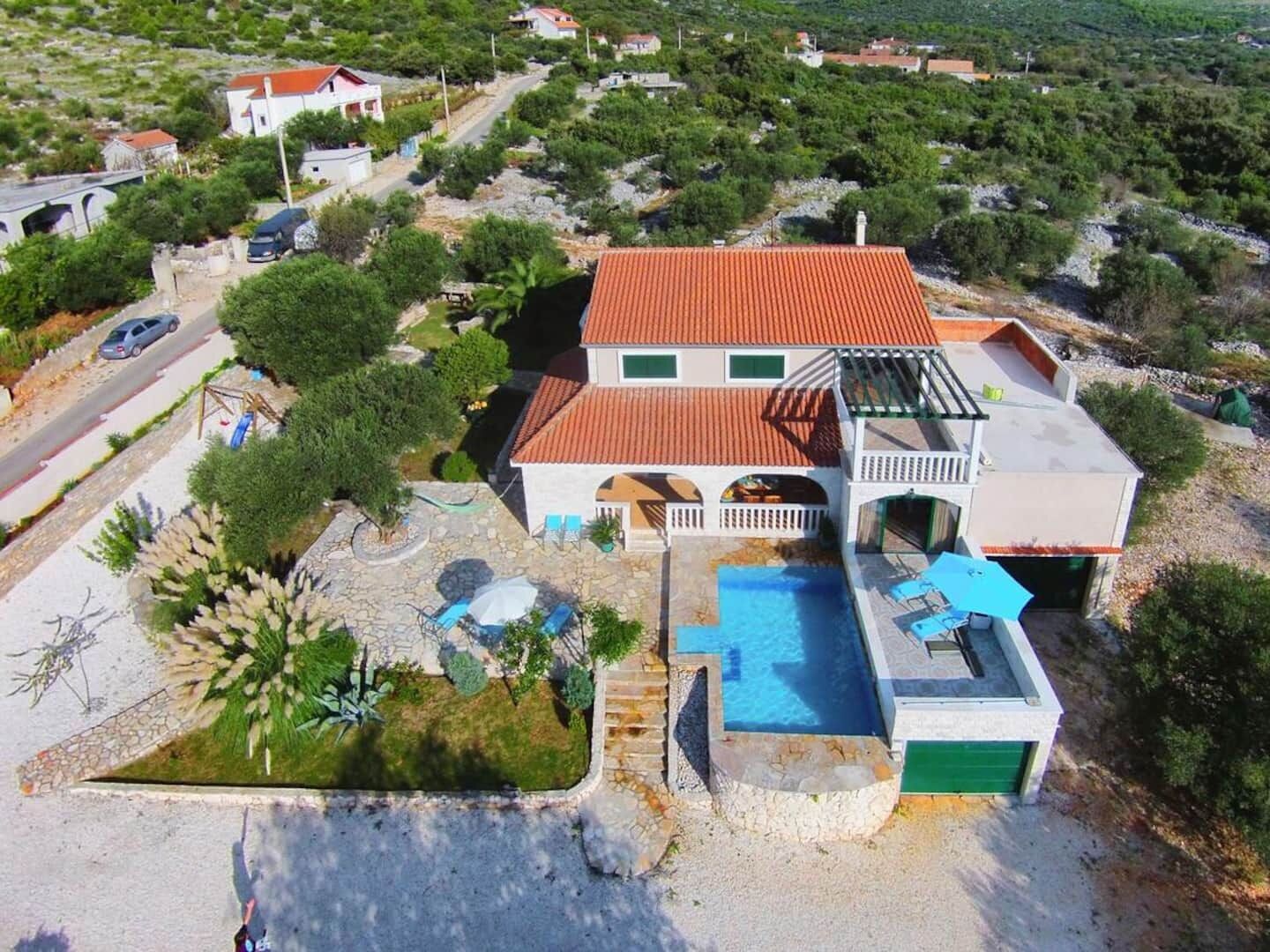 A two-story house with a swimming pool, a covered patio, and a garage.