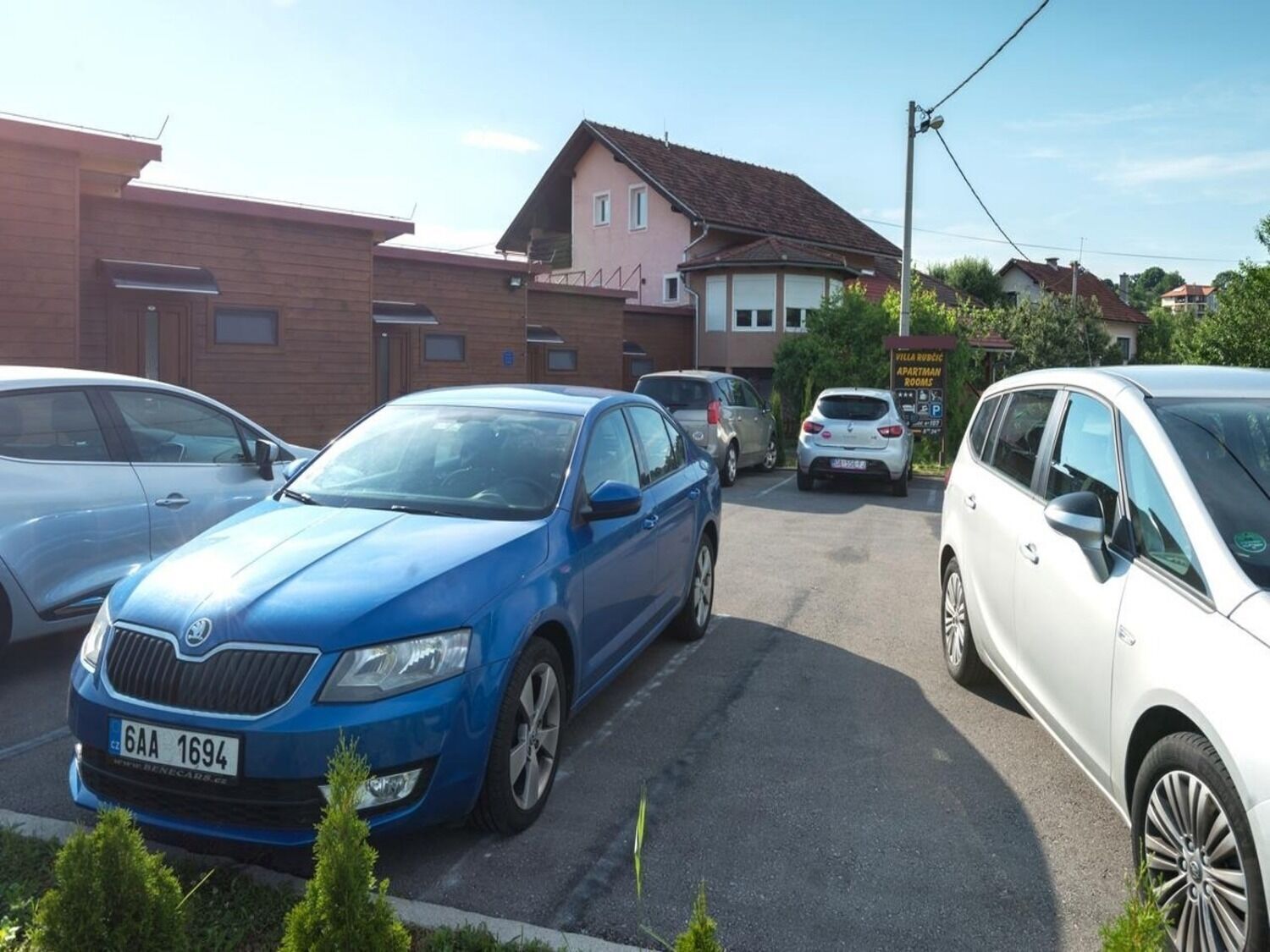 Un espace de stationnement où sont garées plusieurs voitures, dont une berline bleue et un VUS blanc.