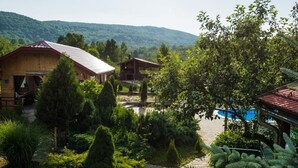 Un complexe hôtelier comprenant plusieurs chalets en bois, une piscine et un jardin bien entretenu avec divers arbustes et arbres.