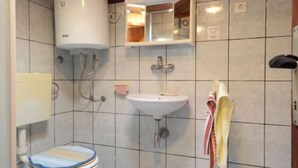 A small bathroom with a toilet, sink, and shower. - Apartments Lukovac (Blato)