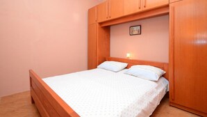 A bedroom with a wooden bed frame, two pillows, and a nightstand with a lamp. - Apartments Lukovac (Blato)