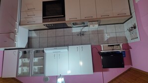 A kitchen with white cabinets, a black oven, and a sink. - Apartments Lukovac (Blato)