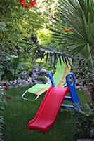 Un jardín con un tobogán y una silla verde.