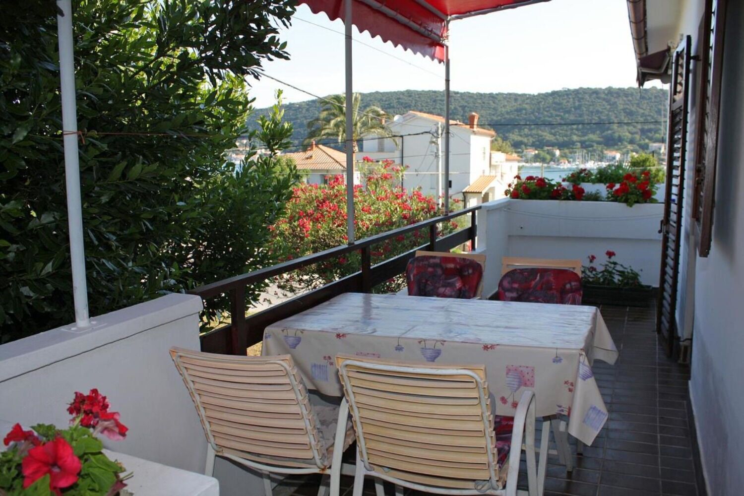 Un balcon avec une table et des chaises, offrant une vue panoramique sur les maisons et les collines.