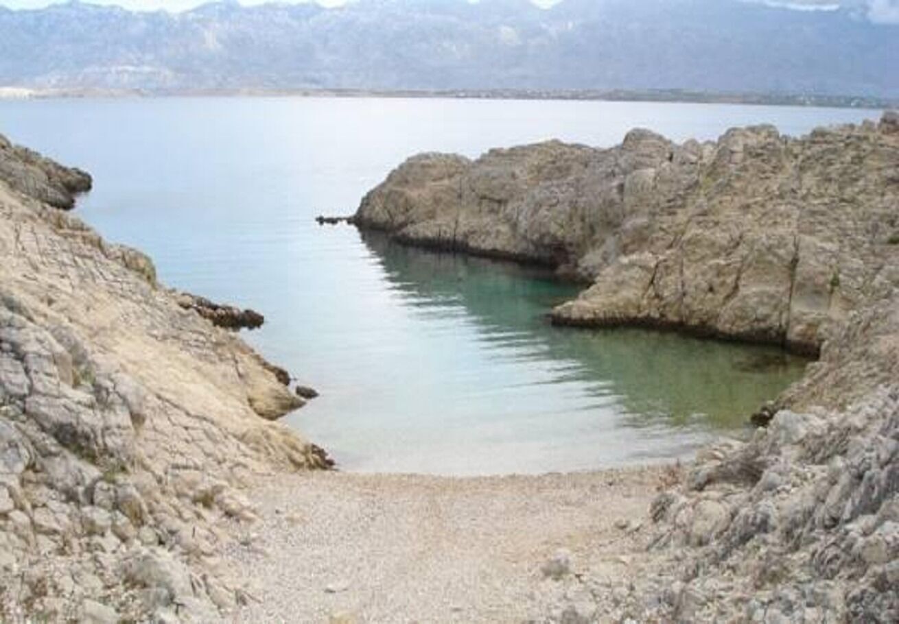 Una costa rocosa con aguas tranquilas y montañas a lo lejos.
